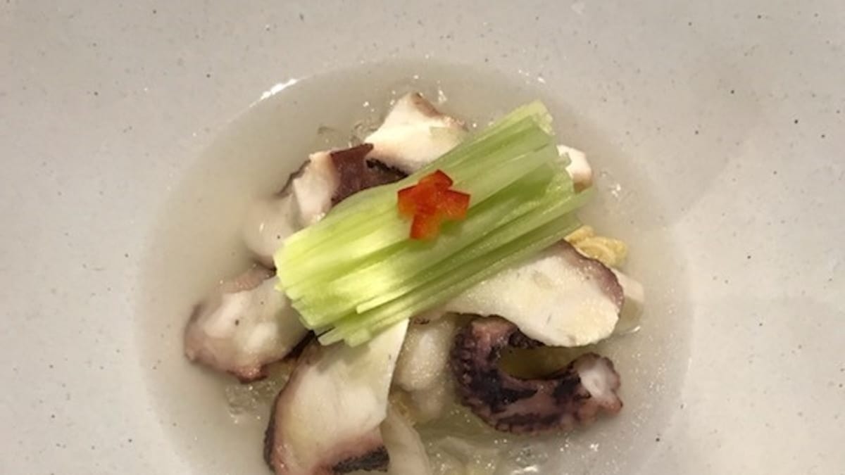 White kimchi with octopus, pale and delicate in a shallow bowl