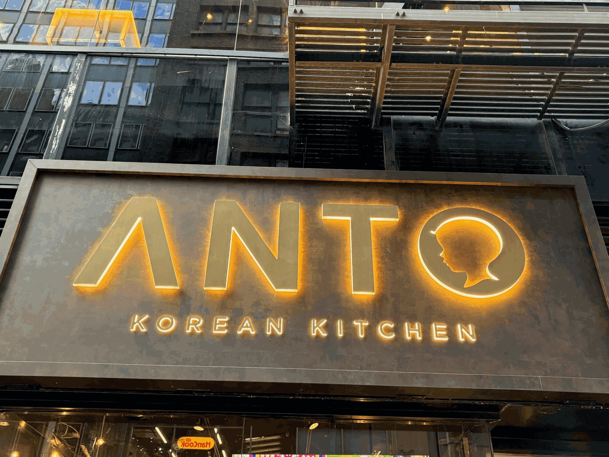 The Anto sign over 32nd Street, glowing gold on bronze